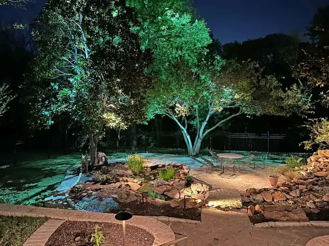 Backyard water feature and flagstone patio in Colleyville, Texas with uplit magnolia and oak overhead