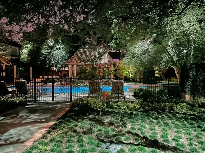 Pool and tile-roofed cabana in Preston Hollow, Dallas seen through a moonlit oak canopy